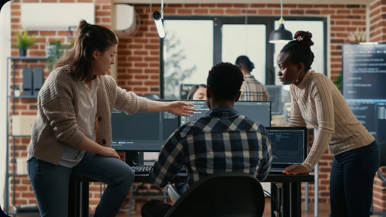 Three engineers reviewing code together at a workstation